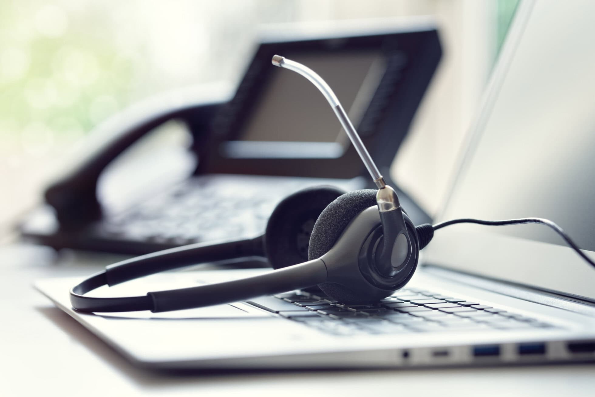 CoWorkSpace Office Equipment Headset and phone on a laptop for remote work.