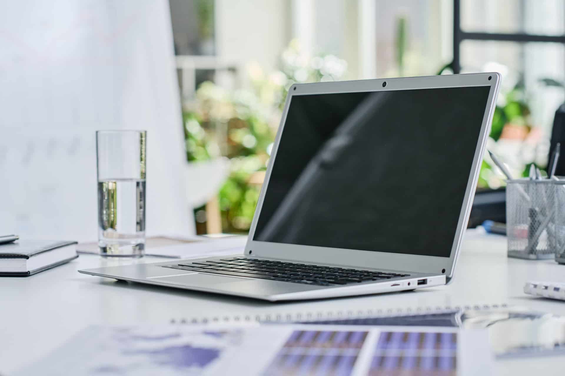 Modern coworking space with laptop and glass of water on desk.