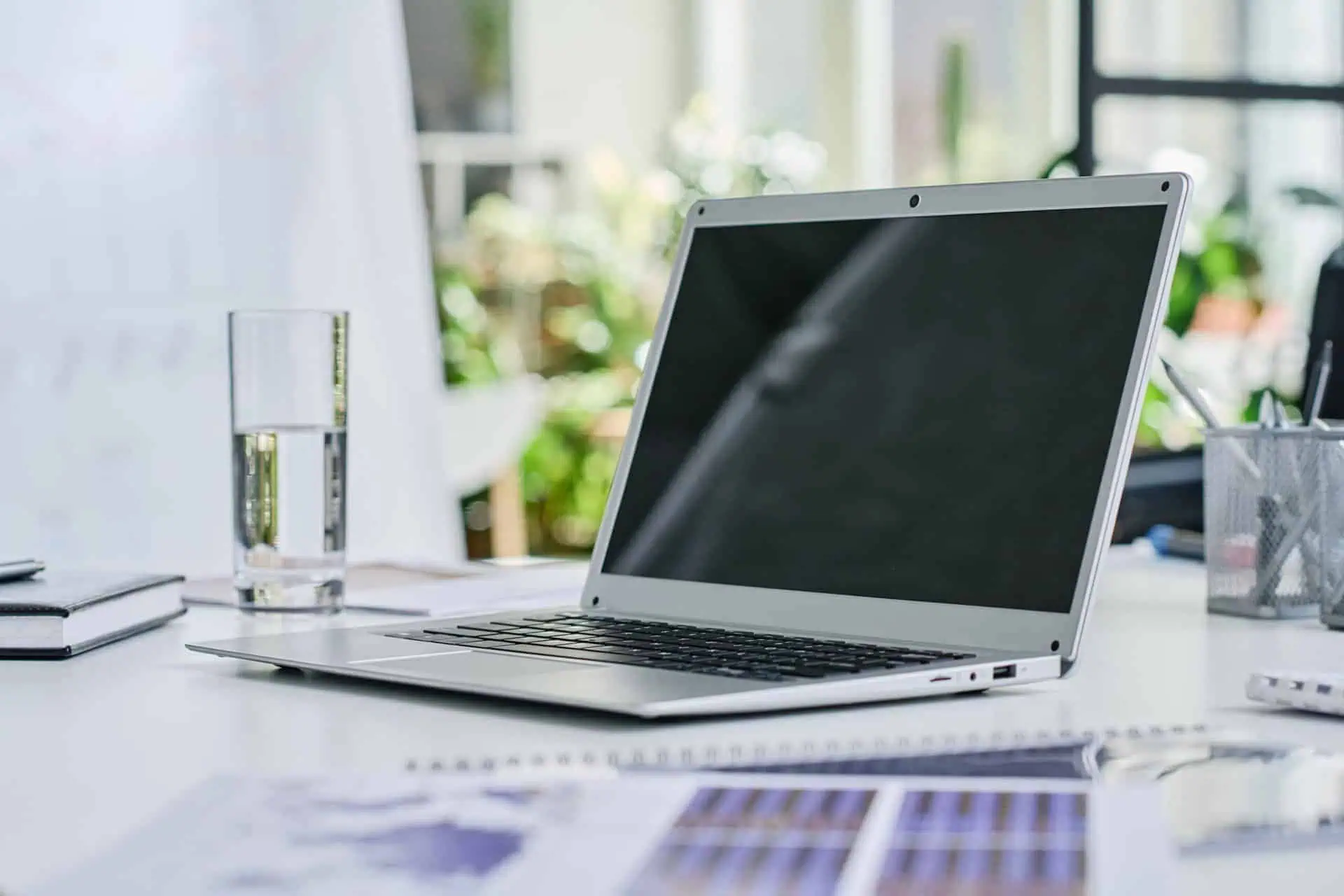 Modern coworking space with laptop and glass of water on desk.