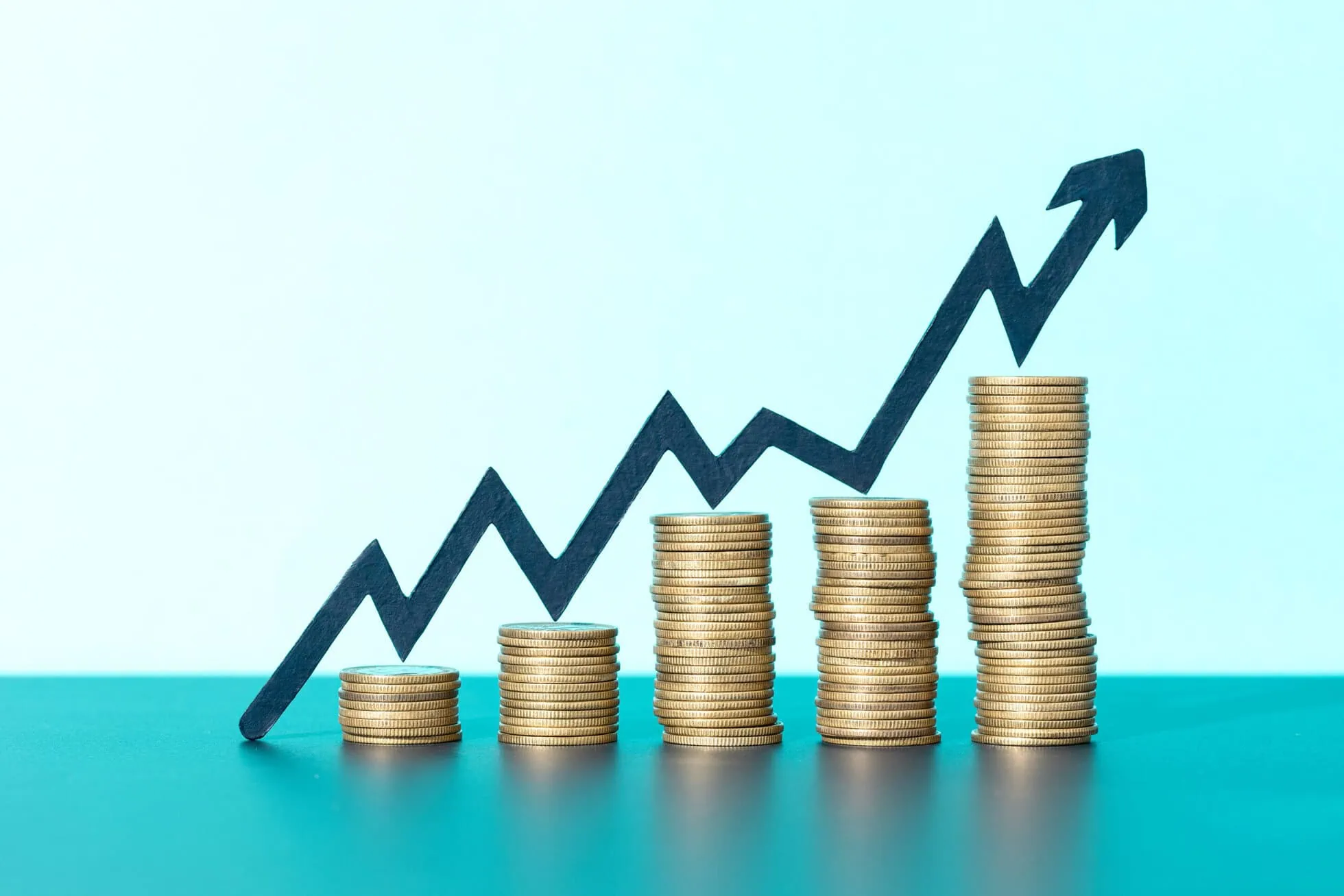 Growing sales graph with ascending stacks of coins and upward arrow.