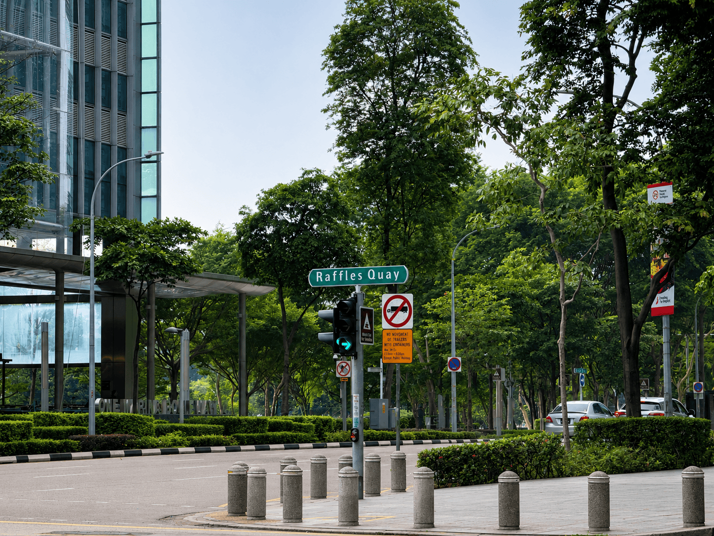 City street scene with trees, traffic lights, and a sign for Raffles Quay.