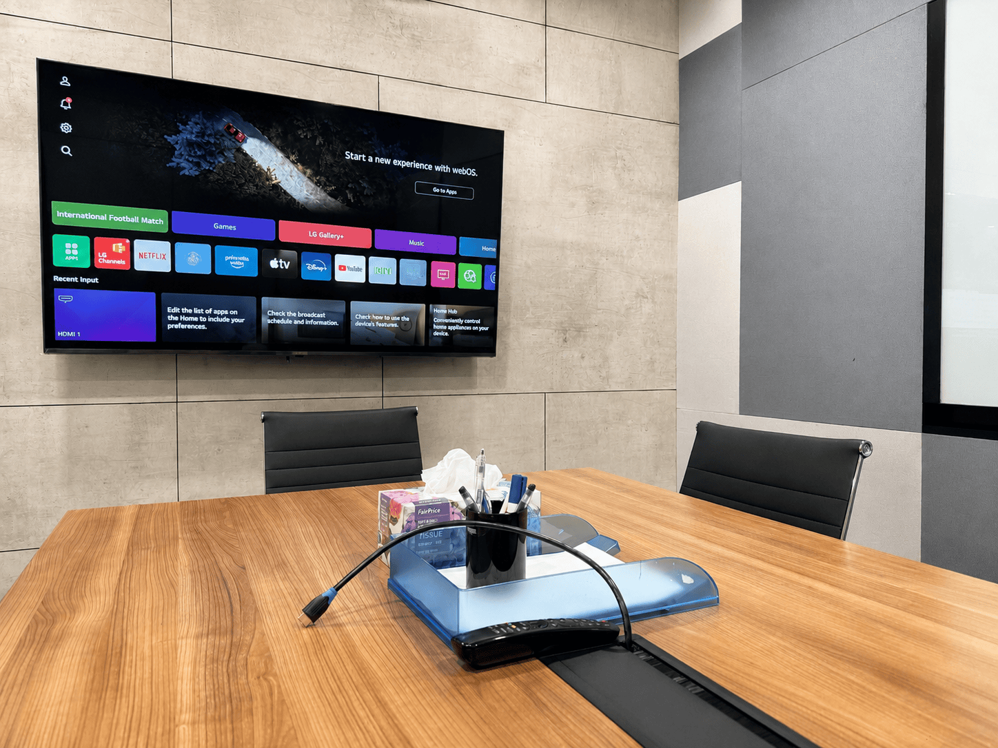 Coworkspace Modern Meeting Room A with Smart TV Modern coworking space with a large TV screen and a wooden conference table.