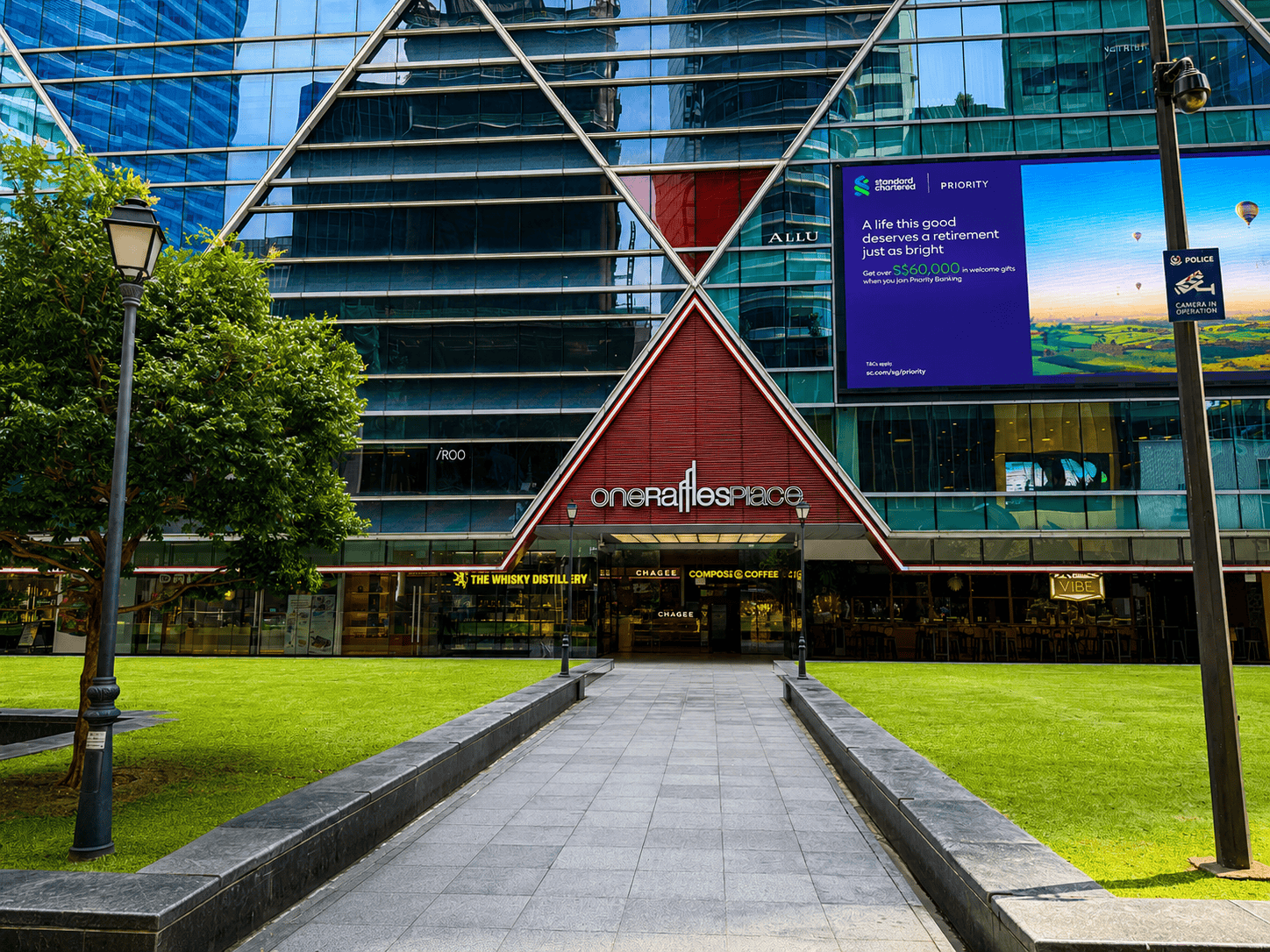 One Raffles Place Main Entrance Modern coworking space building with glass facade and digital billboard in Singapore.