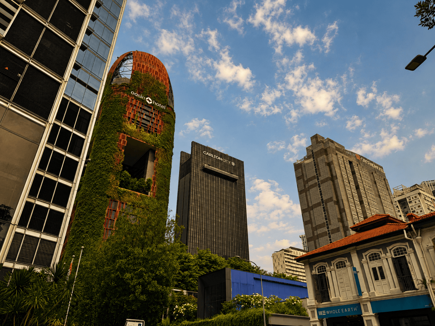 Modern Singapore cityscape with skyscrapers and historic building under blue sky.