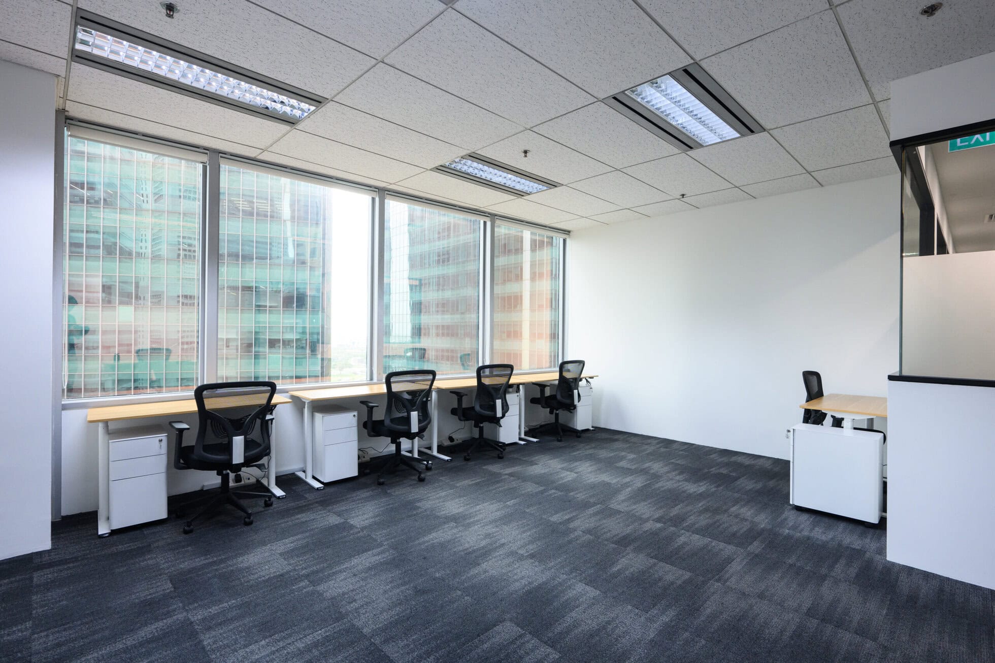 serviced office Modern coworking space with desks and chairs near large windows in Singapore.